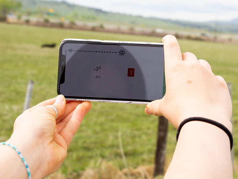 Person using the slope meter in a cow pasture