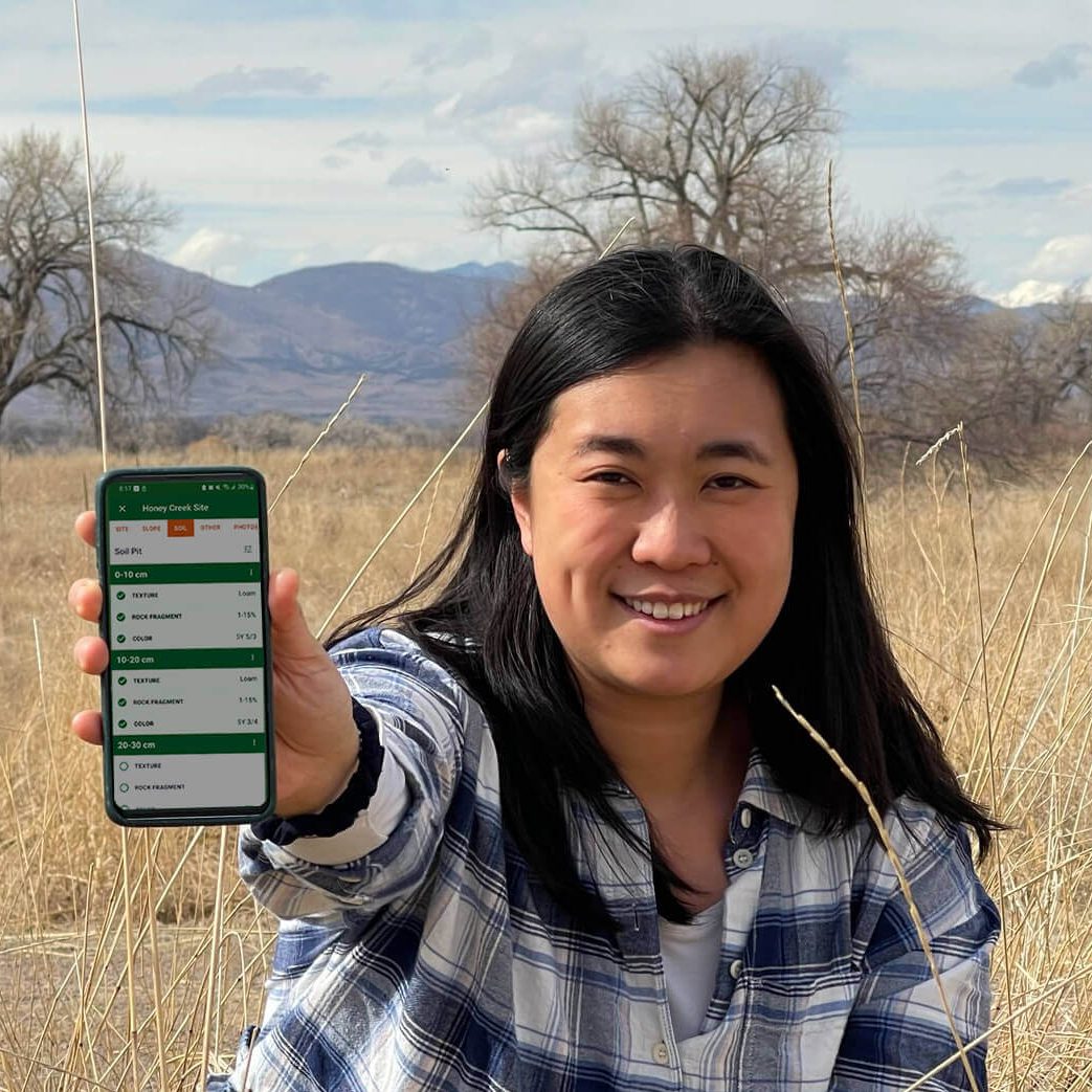 A woman in a rangeland with LandPKS Soil ID app